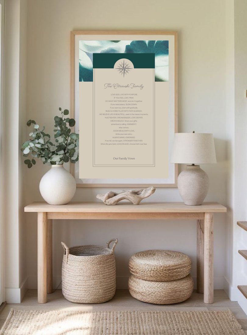 A framed Family Vows print displayed on a console table beside a vase of eucalyptus and a lamp